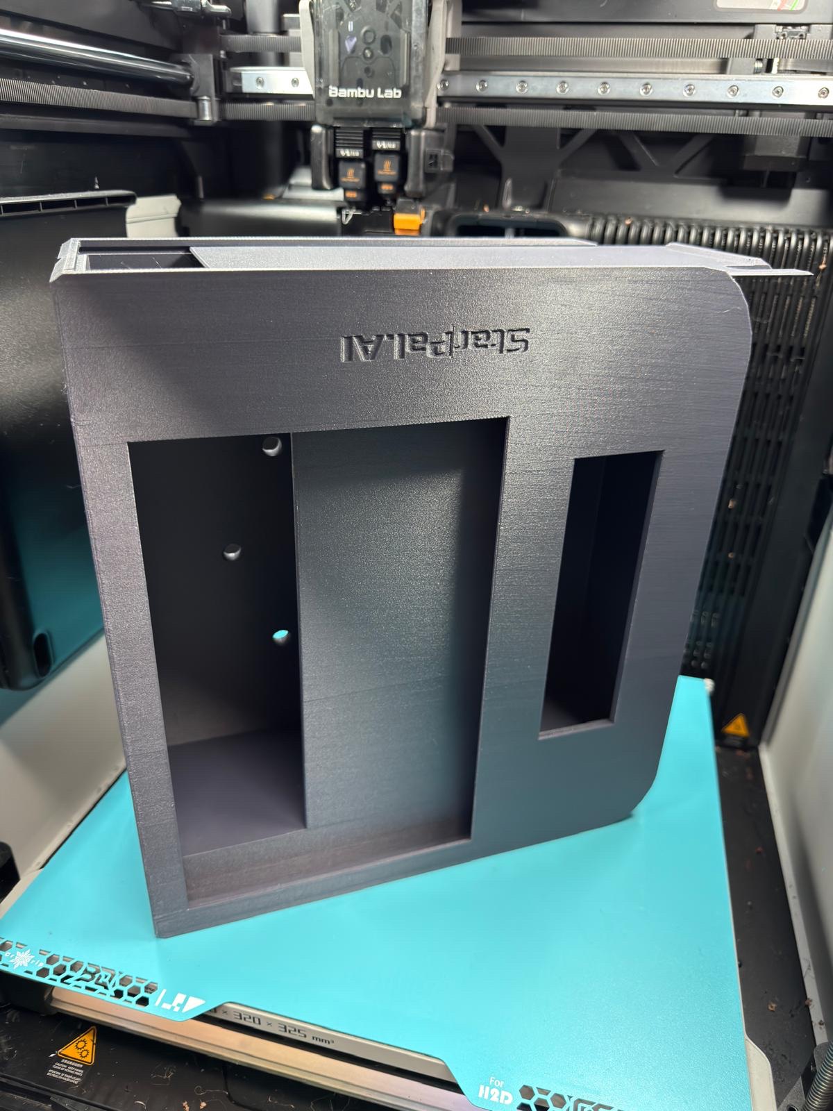 Black custom case with separate openings and StratPal AI lettering on a 3D printer bed